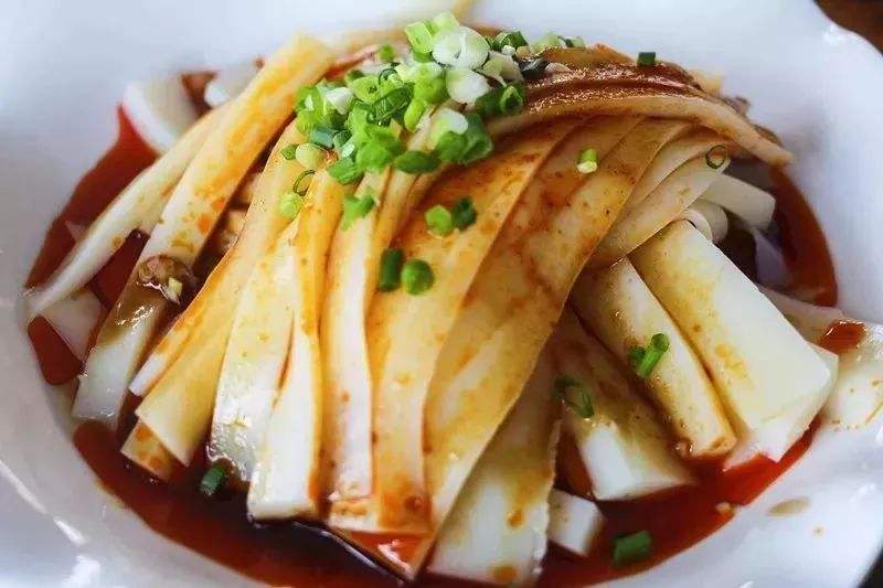 原料及配料： 干豌豆、红油、麻油、花椒油、酱油、辣椒粉、醋、味精、蒜水、油炸黄豆等适量。 制作过程： 1、豌豆淘洗干净，浸泡4个小时，用磨磨成粉浆，用石灰水点后待其冷却成型，食用时切成细条状。 2．用大蒜打成蓉制成蒜水。 3．用甜面酱加入适量清水、白糖制成面酱汁。 4．干辣椒炒脆用粉碎机打成细粉状加入麻油、花生油、花椒油制成辣椒酱。 5．凉粉切成条，淋上辣椒酱拌匀即成。